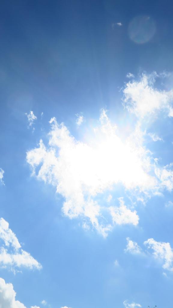 Sonne hinter einer kleinen Wolke am blauen Himmel